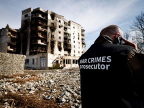 Ein Teammitglied der Staatsanwaltschaft für Kriegsverbrechen telefoniert neben Gebäuden, die während der russischen Invasion in der Ukraine durch russischen Beschuss zerstört wurden, in Borodyanka, Region Kiew, Ukraine, Donnerstag, 7. April 2022.