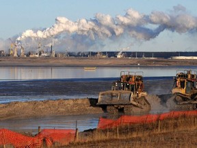 Workers use heavy machinery in the tailings pond at the Syncrude oil sands extraction facility near the town of Fort McMurray in Alberta on Oct. 25, 2009.