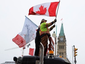 Menschen schwenken Fahnen auf einem Lastwagen vor dem Parliament Hill, während Lastwagenfahrer und ihre Unterstützer am 6. Februar 2022 in Ottawa weiterhin gegen die COVID-19-Impfstoffmandate protestieren.
