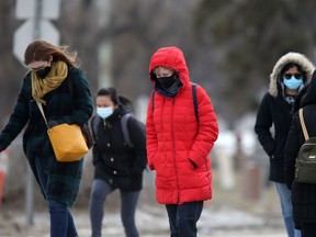 People wear masks while crossing a street in Winnipeg on Tuesday.