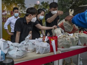 Restaurantmitarbeiter geben am 5. Mai 2022 in Peking, China, Essen zum Mitnehmen an Kurierfahrer vor einem Einkaufszentrum weiter, nachdem die Regierung das Essen im Inneren verboten hatte, um die Ausbreitung von COVID-19 zu verhindern.