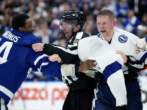 Officials separate Toronto Maple Leafs forward Wayne Simmonds (24) and Tampa Bay Lightning forward Corey Perry (10) as they fight during third period, round one, NHL Stanley Cup playoff hockey action in Toronto, Monday, May 2, 2022.