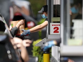 Orders are collected through a drive-through window as staff are seen wearing PPE equipment to hand over orders on a tray to minimize contact at the Burger King drive-through in Havant, their first branch to reopen during coronavirus lockdown on May 01, 2020 in Havant, Portsmouth. (Photo by Naomi Baker/Getty Images)