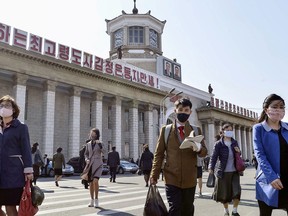 People wearing protective face masks walk amid concerns over the new coronavirus disease (COVID-19) in front of Pyongyang Station in Pyongyang, North Korea April 27, 2020, in this photo released by Kyodo.