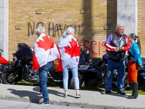 People wrapped in Canadian flags arrive at Bikers Church following the motorcycle-borne "Rolling Thunder Ottawa" protest in Ottawa May 1, 2022.