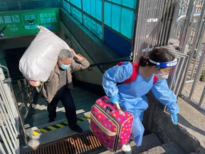 Reisende mit Gepäck verlassen eine U-Bahn-Station am ersten Tag der Wiederaufnahme von Teilen des U-Bahn-Dienstes der Stadt in Shanghai, China, 22. Mai 2022.