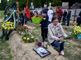 People pay respect next to graves at Lychakiv Cemetery where people killed in Russia's invasion of Ukraine are buried as the Day of Heroes of Heavenly Hundred is celebrated, in Lviv, Ukraine May 22, 2022.