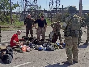 Service members of Ukrainian forces who have surrendered after weeks holed up at Azovstal steel works are being searched by the pro-Russian military in Mariupol, Ukraine, in this still image taken from a video released May 18, 2022.