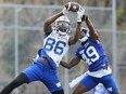 Receiver Carlton Agudosi (left) grabs a pass in front of defensive back Corey Straughter during Winnipeg Blue Bombers rookie camp at Winnipeg Soccer Federation South Complex on Thursday.