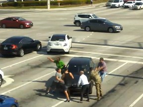 A group of bystanders helps stop a vehicle at a busy intersection after a woman had a medical episode in Boynton Beach, Fla.