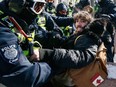 A police officer grapples with a man as authorities work to remove the Freedom Convoy protest in downtown Ottawa on Feb. 18, 2022.