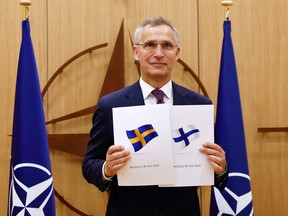 NATO Secretary-General Jens Stoltenberg poses with application documents presented by Finland's Ambassador to NATO Klaus Korhonen and Sweden's Ambassador to NATO Axel Wernhoff during a ceremony to mark Sweden's and Finland's application for membership in Brussels, on May 18, 2022.