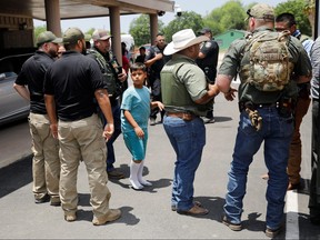 A child gets on a school bus as law enforcement personnel guard the scene of a suspected shooting near Robb Elementary School in Uvalde, Texas, May 24, 2022.