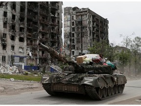Service members of pro-Russian troops drive a tank along a street past a destroyed residential building during Ukraine-Russia conflict in the town of Popasna in the Luhansk Region, Ukraine May 26, 2022.