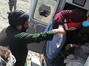 This photograph taken on June 22, 2022 and received as a courtesy of the Afghan government-run Bakhtar News Agency shows a member of the Afghan Red Crescent Society giving medical treatment to a victim following an earthquake in Afghanistan's Gayan district, Paktika province. (Photo by Bakhtar News Agency / AFP)