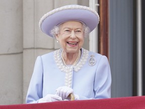 Königin Elizabeth lächelt, als sie vom Balkon des Buckingham Palace nach der Trooping the Colour-Zeremonie in London am Donnerstag, den 2. Juni 2022, am ersten von vier Tagen der Feierlichkeiten zum Platinjubiläum zusieht.  (Jonathan Brady/Pool-Foto über AP)