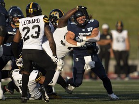 Argonauts running back AJ Ouellette is tackled by Hamilton Tiger-Cats defensive tackle Ted Laurent during the first half of preseason CFL football action in Guelph, Ont., Friday, June 3, 2022.