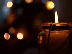 This file photo shows a candle burning with flame in the dark.