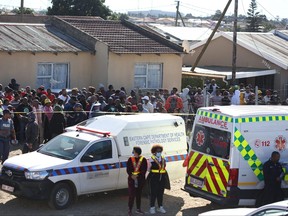 Menschenmassen versammeln sich, während forensisches Personal nach dem Tod von Gästen ermittelt, die in der Enyobeni Tavern im Scenery Park außerhalb von East London in der Provinz Eastern Cape, Südafrika, am 26. Juni 2022 gefunden wurden.
