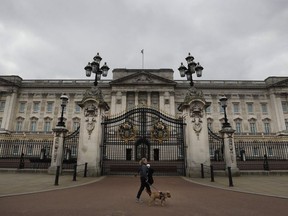 A dog walker passes a quiet Buckingham Palace, in London, March 23, 2021.