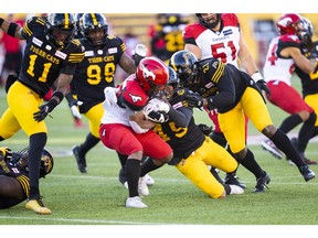Stampeders running back Peyton Logan runs the ball against the Hamilton Tiger-Cats' Jovan Santos-Knox during first-half CFL action in Hamilton on Saturday. The Stamps won 33-30.