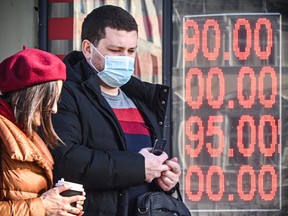 People walk past a currency exchange office in central Moscow on Feb. 28, 2022, with zeros on the scoreboard since there are no three-digit sections on it to display the current exchange rate.