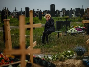 A woman mourns while visiting the grave of Stanislav Hvostov, 22, a Ukrainian serviceman killed during the Russian invasion of Ukraine, in Bezlioudivka, eastern Ukraine on May 21, 2022.