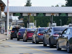 A line of vehicles wait to enter Canada at the Peace Arch border crossing in Blaine, Wash., Aug. 9, 2021.