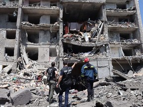 Ein Staatsanwalt für Kriegsverbrechen (Mitte) und ein Retter (rechts) und ein Zivilist schauen sich ein zerstörtes Gebäude an, nachdem es am Freitag, den 1. Juli 2022 in der ukrainischen Stadt Sergiyvka in der Nähe von Odessa von einem Raketenangriff getroffen wurde.