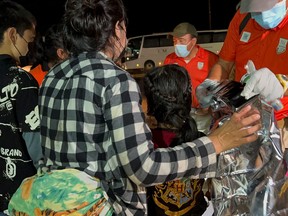 Agenten des mexikanischen Nationalen Instituts für Migration (INM) helfen einer Gruppe von Migranten, nachdem sie zusammen mit anderen Migranten gerettet wurden, die am 27. Juli 2022 in der Stadt Acayucan im mexikanischen Bundesstaat Veracruz in einem Wohnwagen zurückgelassen wurden.
