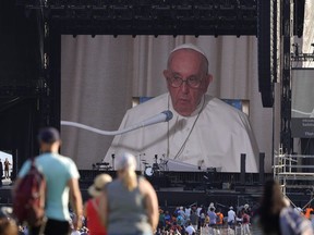 Die Menschen beobachten einen Bildschirm, während Papst Franziskus am Mittwoch, den 27. Juli 2022, eine Ansprache in der Zitadelle in Quebec City hält.