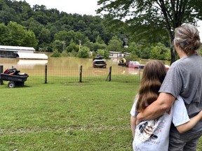 Bonnie Combs, right, hugs her 10-year-old granddaughter Adelynn Bowling as they watch her property be inundated by the North Fork of the Kentucky River in Jackson, Ky., Thursday, July 28, 2022.
