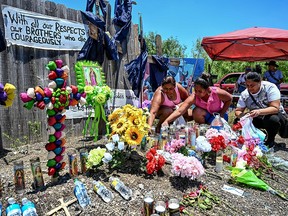 Menschen platzieren Blumen und Kerzen an einem provisorischen Denkmal, an dem am 29. Juni 2022 außerhalb von San Antonio, Texas, ein Sattelzug mit Migranten entdeckt wurde.