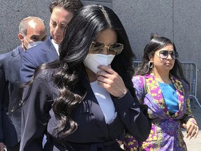 Jennifer Shah, middle, of "The Real Housewives of Salt Lake City" reality television series, touches her face mask as she leaves Manhattan federal court in New York, Monday July 11, 2022.