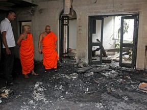 People stand amid debris inside the residence of Sri Lanka's Prime Minister, a day after it was vandalized by the protesters in Colombo on July 10, 2022.