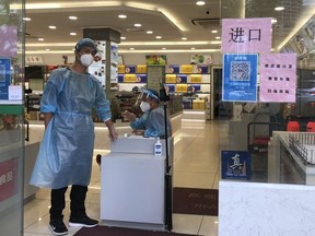 Arbeiter in Schutzausrüstung überwachen am Mittwoch, den 6. Juli 2022, in Shanghai den Eingang zu einem Geschäft.