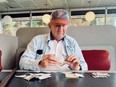 Man sits at table with money and notes, holding note that reads 'love every body'