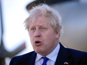Der britische Premierminister Boris Johnson reagiert, als er sich am 14. April 2022 mit Besatzungen und technischem Personal der HM Coastguard und der Royal Navy am Flughafen Lydd im Südosten Englands trifft.