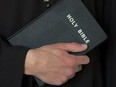 Priest holding bible with crucifix.