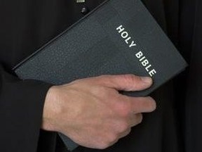 Priest holding bible with crucifix.