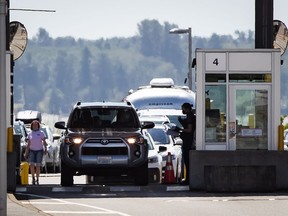 Ein Beamter der Canada Border Services Agency spricht mit einem Autofahrer, der am 9. August 2021 am Grenzübergang Douglas-Peace Arch in Surrey, BC, nach Kanada einreist.