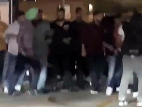 A man (in green turban) appears to swing a sword during a brawl in a Brampton parking lot.