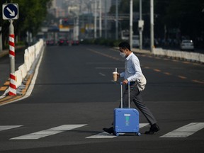 A man pushes his luggage across a street in Beijing on August 30, 2022.