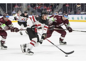 Canada's Ridly Grieg (17) is chased by Latvia's Peteris Purmalis (20) and Bogdans Hodass (17) during second period IIHF World Junior Hockey Championship action in Edmonton on Wednesday, Aug. 10, 2022.