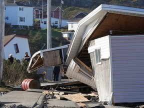 People remove items from damaged buildings that were moved from their position in the aftermath of Hurricane Fiona in Port Aux Basques, Newfoundland and Labrador, Sunday, Sept. 25, 2022.