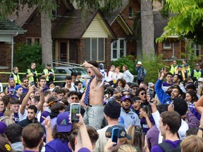 Crowds gather to watch one reveller perform back flips on a trampoline that was carried onto a lawn on Broughdale Avenue during Homecoming festivities near the Western University campus. Photo taken Saturday Sept. 24, 2022. (Calvi Leon/The London Free Press)