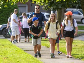 Jason Yeo walks with his kids Tyler, 8, their friend Katie Vilon, 12, (obscured Nathan, 5) and Britton Yeo, 10, on their first day of school on Sept. 7, 2021. (Mike Hensen/The London Free Press)