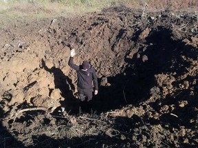A police officer stands on a bottom of a crater left by a Russian military strike at a compound of the Pivdennoukrainsk Nuclear Power Plant in Mykolaiv region, Ukraine, in this handout picture released September 19, 2022.