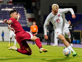 Qatar's Alrawi, left, tries tp stop Canada's Liam Millar during the international friendly soccer match between Qatar and Canada, at the Viola Park stadium in Vienna, Austria, Friday, Sept. 23, 2022.