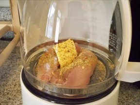 Clear coffee pot with raw chicken and garlic inside.